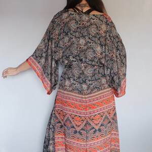 May include: A long, black and orange patterned kimono with a floral design. The kimono has a wide, flowing silhouette and a tie belt.