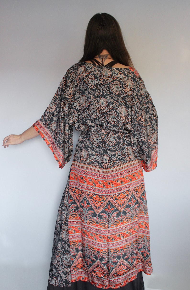 May include: A long, black and orange patterned kimono with a floral design. The kimono has a wide, flowing silhouette and a tie belt.