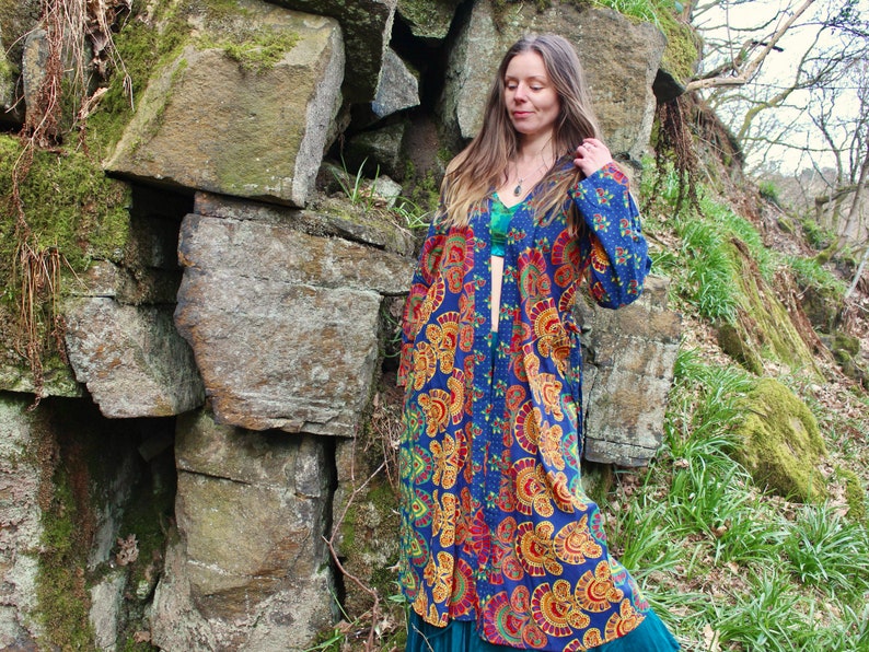 May include: A long, blue and orange patterned kimono with a floral design. The kimono is open in the front and has a belt.