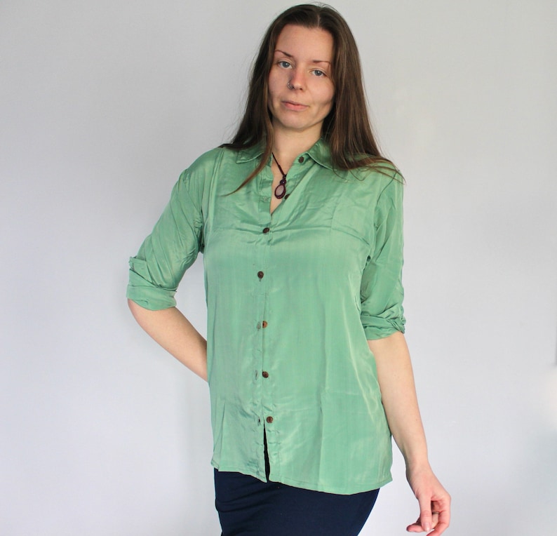 Puede incluir: Una camisa de manga larga de color verde claro con botones y cuello. La camisa est&aacute; hecha de un material sedoso y tiene un corte holgado.