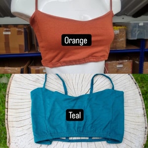 May include: Two crop tops, one orange and one teal, with adjustable straps. The tops are made of a soft, stretchy fabric.