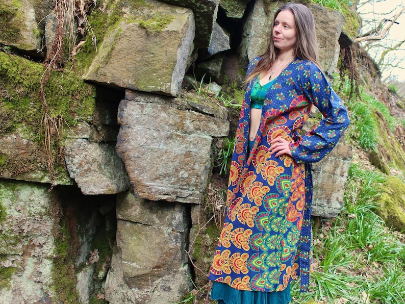 May include: A long, blue and orange patterned kimono with a tie closure. The kimono is worn over a teal blue top and a silver necklace.
