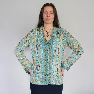 Op de afbeelding: Een lang mouw, lichtblauw shirt met een paisley-patroon. Het shirt heeft een knoopsluiting aan de voorkant en een kraag. Het shirt is gemaakt van een zachte, vloeiende stof.