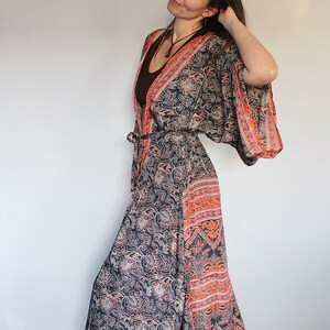 May include: A long, flowing black and orange patterned robe with a tie belt. The robe has a floral print and a wide, flowing sleeve.