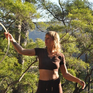 May include: A dark brown short-sleeved V-neck crop top paired with matching dark brown leggings. The top features a fitted silhouette, while the leggings have a high-waisted design with a drawstring detail at the center of the waistband.