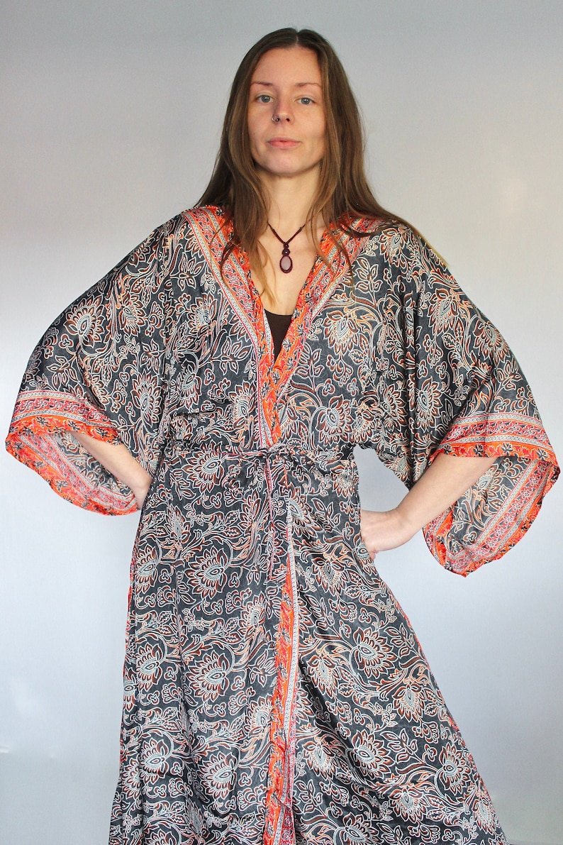 May include: A long, black and orange patterned kimono with a floral design. The kimono has a sash tie at the waist and long sleeves.