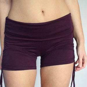 May include: Purple yoga shorts with a drawstring detail on the sides.