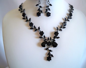 Può includere: Un set di collana e orecchini neri con un design floreale e accenti di cristallo nero.