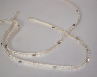 May include: Two ivory satin ribbons with white beads and silver rhinestones. The ribbons are tied together in a knot.