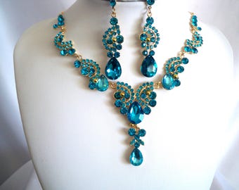 Può includere: Un set di collana e orecchini in tonalità oro e blu turchese con un design a forma di lacrima. La collana ha un ciondolo con una grande pietra a forma di lacrima.