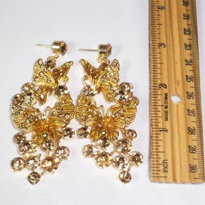 Puede incluir: Pendientes de mariposa dorados con pedrer&iacute;a transparente y color &aacute;mbar. Los pendientes tienen un dise&ntilde;o colgante con cierre de poste. Los pendientes miden aproximadamente 7.6 cm de largo.