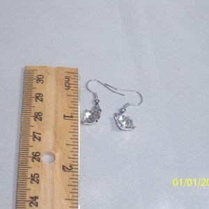May include: A pair of silver earrings with clear crystal stones. The earrings are approximately 1 inch long.