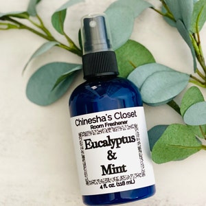 May include: A blue glass bottle with a black spray top and a white label that reads "Chinesha's Closet Room Freshener Eucalyptus & Mint 4 fl oz. (118 mL)"