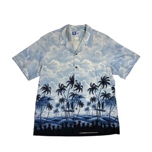 May include: A blue and white short-sleeved button-down shirt with a palm tree and ocean scene print. The shirt has a pocket on the left side and a label that reads "Island Rags".