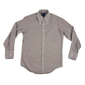 May include: A button-down shirt with a small checkered pattern in brown and white. The long-sleeved shirt has a button-down collar, a chest pocket, and buttoned cuffs. The shirt is laid flat on a white background.