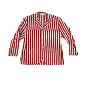 May include: Red and white striped jacket with long sleeves. The jacket has a collared neckline, two front pockets, and three buttons down the front. The vertical stripes are evenly spaced.