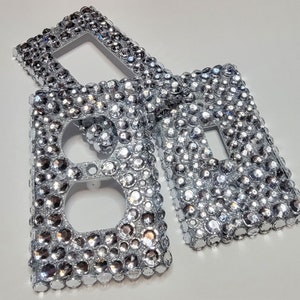 May include: Three silver light switch covers with a diamond-like pattern. The covers are made of plastic and have a shiny finish.