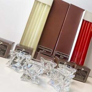 Peut inclure: Un ensemble de cinq bougeoirs en verre transparent en forme d'étoile avec deux boîtes de bougies chauffe-plat blanches et rouges. Les boîtes sont étiquetées "Fines Chandelles Avon".