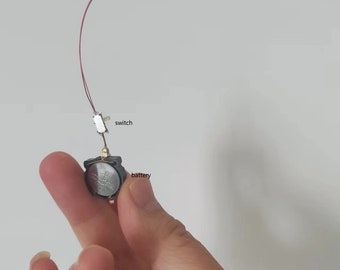 May include: A small, black battery pack with a red and white wire attached to a small, white switch. The wire continues to a small, white light.
