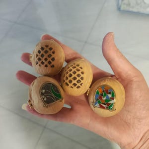 Puede incluir: Cuatro pequeñas cajas de madera con diseños intrincados y acentos de esmalte de colores. Las cajas están talladas en madera y tienen un acabado natural. Cada caja tiene un diseño diferente, que incluye un patrón geométrico, un patrón floral y un patrón geométrico con una luna creciente.