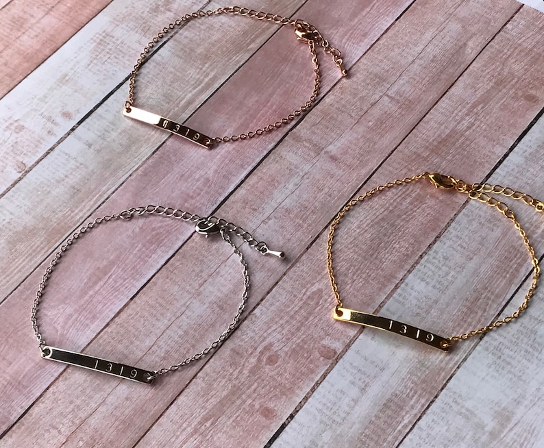 May include: Three gold, silver, and rose gold bracelets with a bar charm engraved with the number "1319".