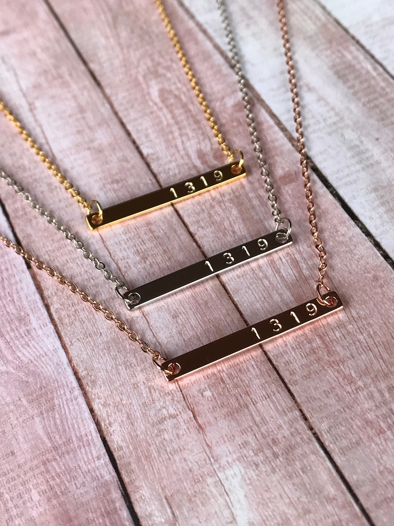 May include: Three gold, silver, and rose gold bar necklaces with the number "1319" engraved on each.