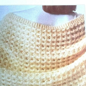 Peut inclure: Un châle en crochet fait à la main, de couleur blanc cassé, avec un motif de tissage ouvert et texturé. Le châle est drapé sur les épaules, mettant en valeur le motif de point complexe et la couleur douce et chaude. Les bords ont une bordure côtelée.