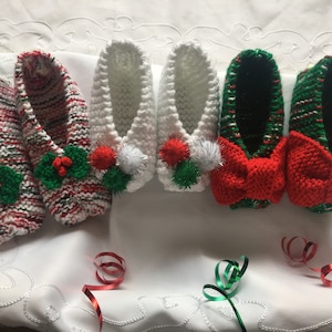 May include: Six pairs of knitted Christmas-themed slippers. Three pairs are white with green and red pom-poms. Three pairs are green and red with red bows.