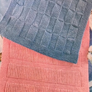 May include: Two knitted blankets, one in a light blue color with a checkered pattern and the other in a pink color with a ribbed pattern.