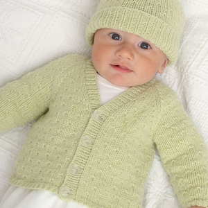 May include: A baby wearing a light green knitted cardigan with buttons and a matching knitted hat.
