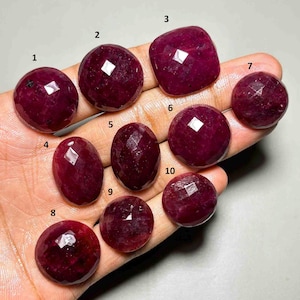 Könnte beinhalten: Zehn facettierte, tiefrote, runde und ovale Edelsteine, die mit den Nummern eins bis zehn beschriftet sind. Jeder Stein hat eine polierte, facettierte Oberfläche, die das Licht reflektiert und einen dunklen Karmesinton aufweist.