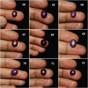 May include: A collection of nine individual oval-shaped cabochon star rubies, each labeled with a number from 64 to 72. These deep red gemstones exhibit a distinct six-rayed star effect, known as asterism, visible on their smooth, polished surfaces.