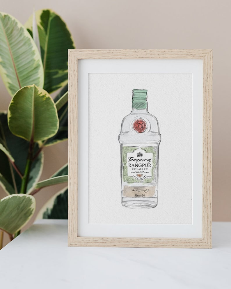 May include: A framed watercolor illustration of a bottle of Tanqueray Rangpur gin. The bottle is green and white with a gold label. The label reads "Tanqueray Rangpur Distilled Gin Made with the Essence of Rangpur Limes."