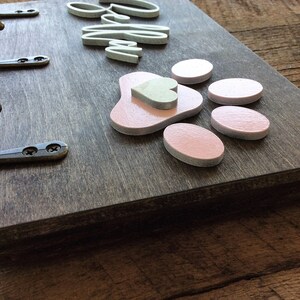 K&ouml;nnte beinhalten: Holz-Schl&uuml;sselhalter mit drei Haken, dem Wort "Willkommen" in wei&szlig;en Buchstaben und einem rosa Pfotenabdruck mit einem kleinen Herz in der Mitte.