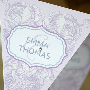May include: A white and purple wedding banner with a floral design and the text "Emma & Thomas" in a blue and purple frame.