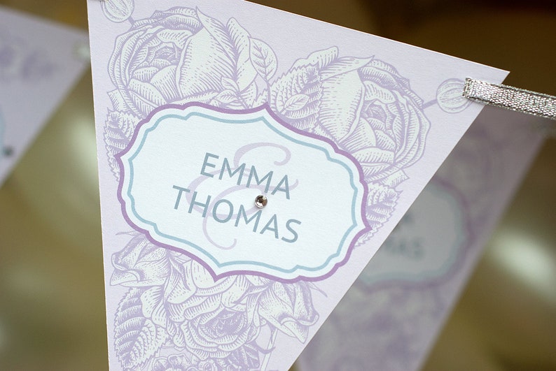 May include: A white and purple wedding banner with a floral design and the text "Emma & Thomas" in a blue and purple frame.