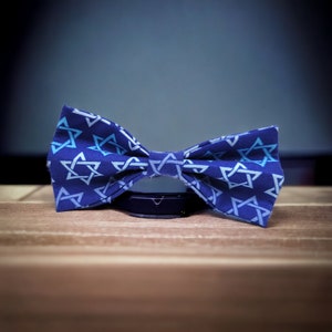 Może przedstawiać: Niebieski krawat muszkowy z białym wzorem gwiazdy Dawida.