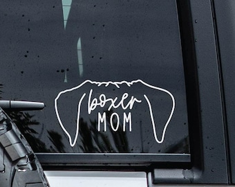 Może przedstawiać: Biała naklejka winylowa na szybę samochodu. Naklejka zawiera napis "boxer MOM" w czcionce skryptowej, z napisem "MOM" w większym rozmiarze. Projekt zawiera kontur uszu boksera.