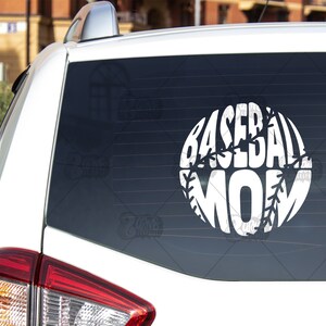 May include: White car with a white vinyl decal on the back window. The decal is a baseball with the word "MOM" inside of it. The number "#3" is printed on the lower right corner of the window.