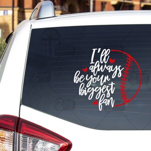 May include: White car with a red baseball graphic and the text "I'll always be your biggest fan" on the back window. The number "#1" is also visible on the window.