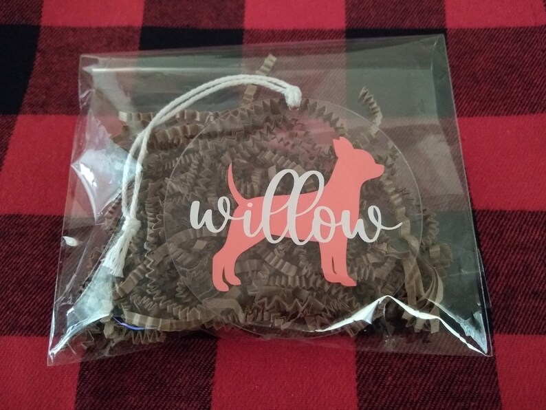 May include: A clear plastic bag with a pink dog silhouette and the word "willow" in white script. The bag is filled with brown crinkled paper.