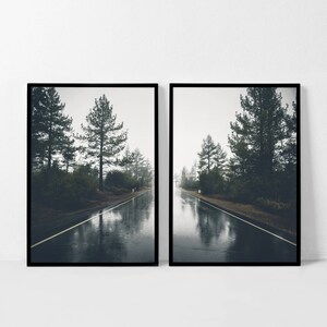 May include: Two framed photographs of a misty road through a forest. The road is wet from rain and reflects the trees and sky. The photos are in black frames.