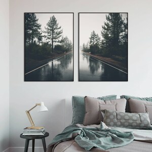 May include: Two framed photographs of a wet road in a forest. The road is lined with trees and the water reflects the sky and trees. The photos are in black frames.