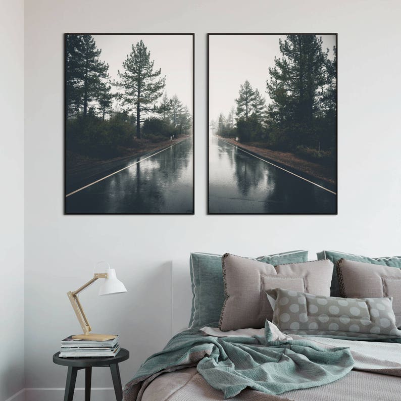 May include: Two framed photographs of a wet road in a forest. The road is lined with trees and the water reflects the sky and trees. The photos are in black frames.