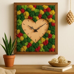 Peut inclure: Une horloge murale encadrée avec un cadran en forme de cœur en bois. Les aiguilles de l'horloge sont noires. L'arrière-plan est rempli de mousse verte, jaune et rouge. Un cône de pin décoratif est suspendu à proximité.