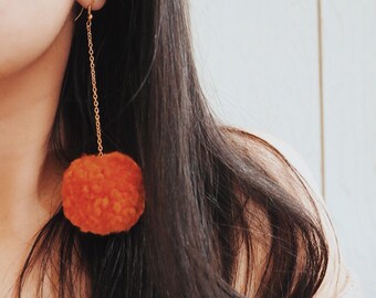 Pendientes largos dorados con pompones naranjas