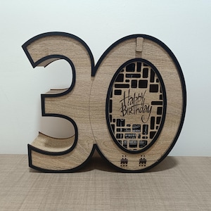 May include: Wooden 30th birthday box with a cutout design and the words "Happy Birthday" inscribed. The box is made of wood with a natural finish and has a black border.