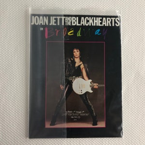 Peut inclure: Panneau en bois fait à la main avec le texte "Welcome" écrit à la main. Le panneau est peint en blanc avec une finition vieillie, et une petite feuille verte est attachée en haut. Le panneau mesure environ 30 cm de large.