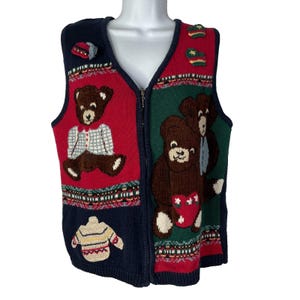 Könnte beinhalten: Eine marineblaue, rote und grüne Weste mit Reißverschluss und Teddybär- und Pullover-Designs. Die Weste hat einen V-Ausschnitt und einen Reißverschluss. Die Teddybären sind braun mit weißen Akzenten.