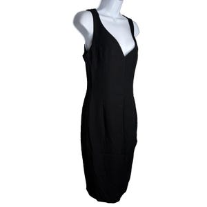 Op de afbeelding: Een zwarte mouwloze jurk met een V-hals. De jurk wordt getoond op een witte mannequin. De jurk heeft een getailleerd silhouet en lijkt gemaakt van een gladde stof. De jurk is knielang.